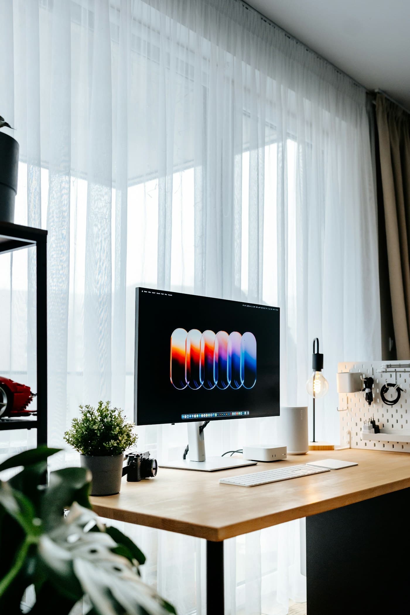 Modern studio desk setup with a computer, plants, and warm lighting