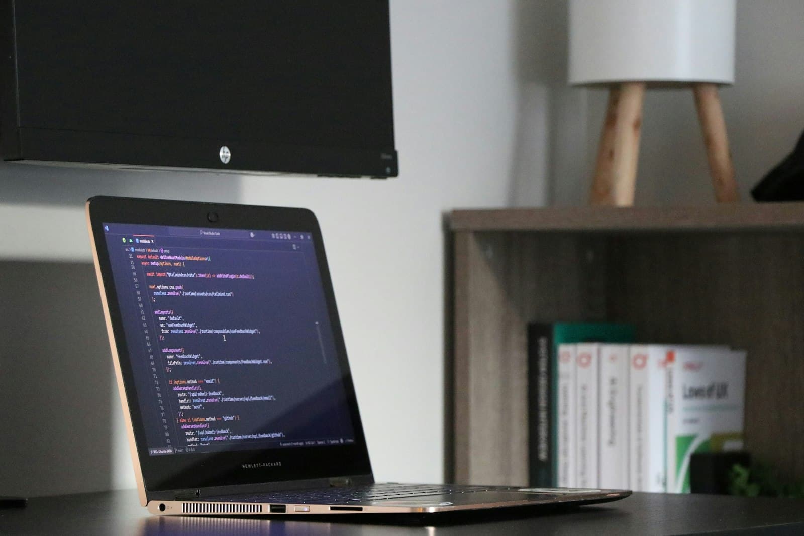 Code editor beside a rendered web UI on a clean desk